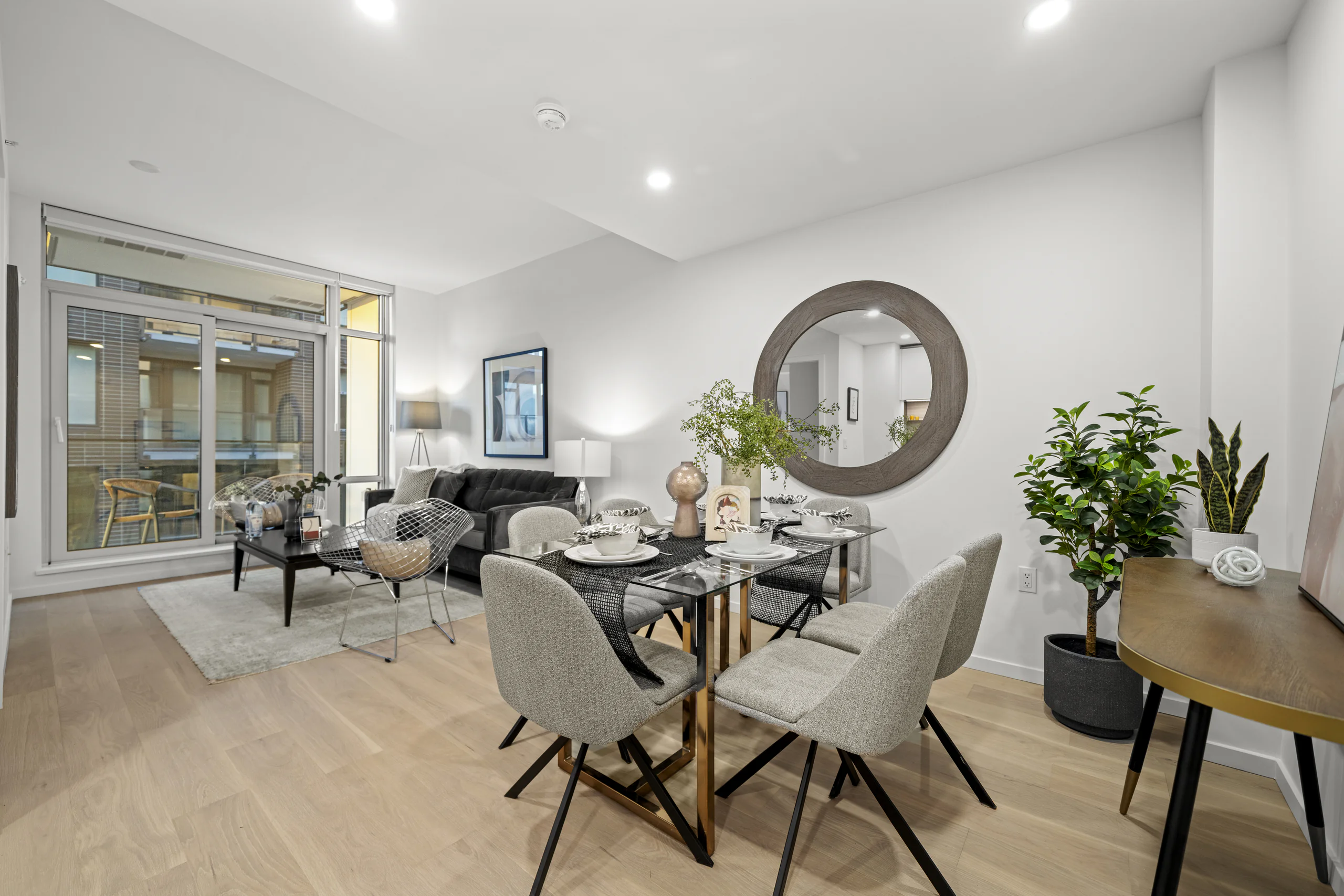Furnished show-suite dining area, with the living room and balcony beyond